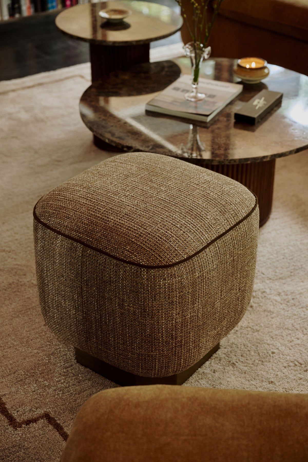 pouf Alyss et fauteuil assorti en tweed beige moucheté dans un salon à cheminée