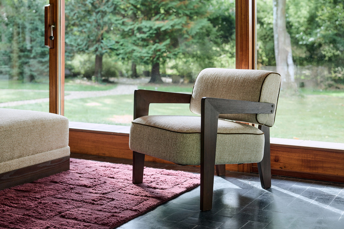 fauteuil Elvia en tissu bouclé écru et structure bois foncé devant la baie vitrée