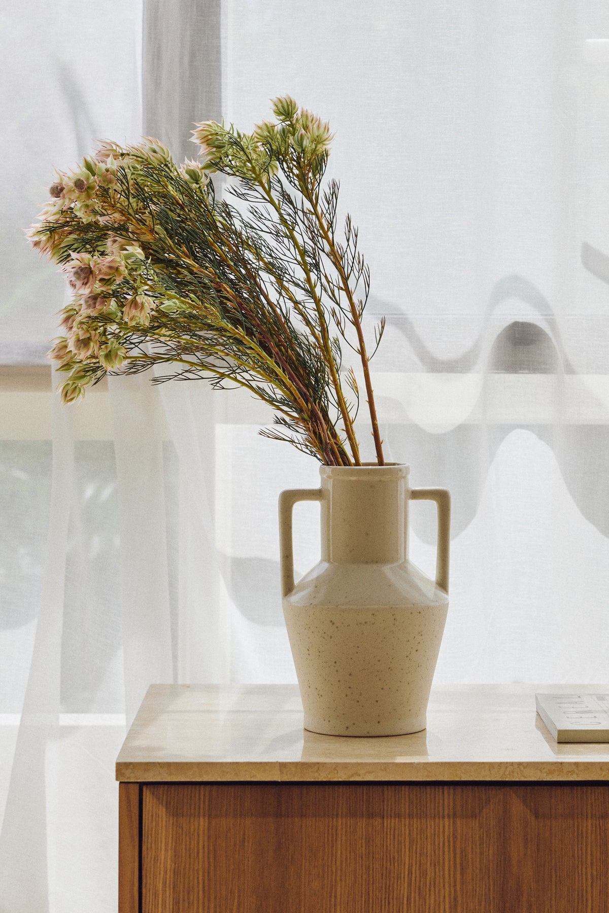 Vase Alda - céramique beige mouchetée, fait main au Portugal - posé sur un buffet en bois
