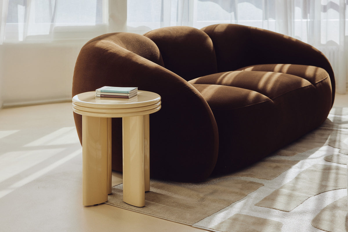 Table d'appoint Mira - NV GALLERY - bois finition beige glossy - au pied d'un canapé velours