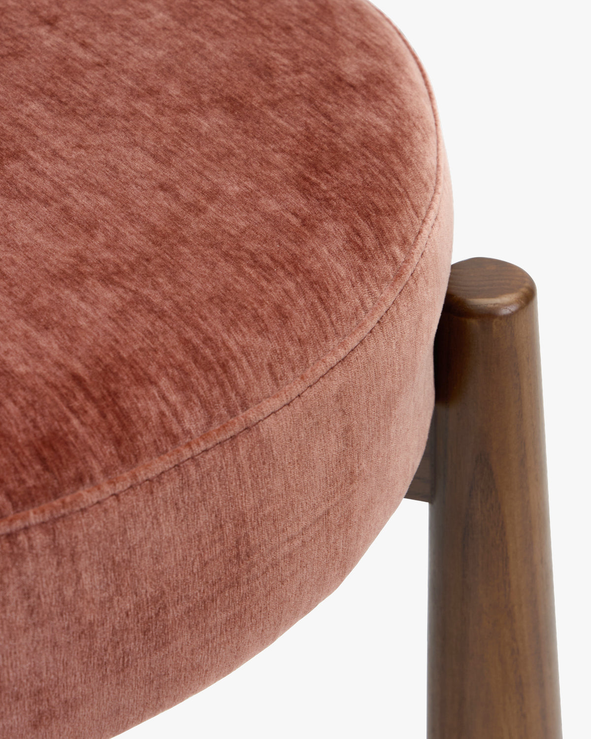 gros plan sur le chant de l'assise en velours chenillé rouge ambré et le pied en frêne d'une chaise UBUD
