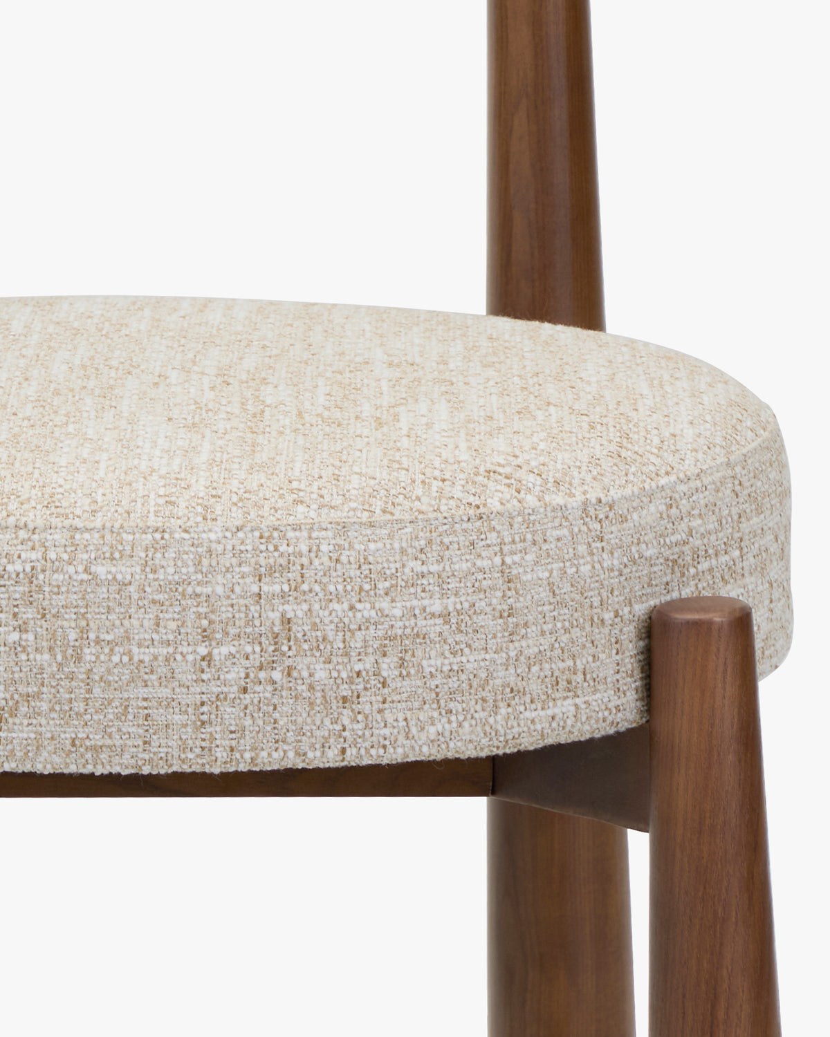 gros plan sur l'assise ronde en tweed écru meringue et les pieds évasés en frêne d'une chaise UBUD